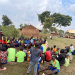 Sharing the gospel: adults under the tent, children under the tree. Uganda Missions 2024